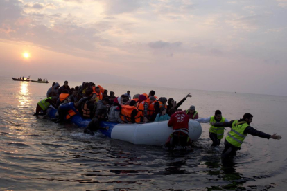 Varios voluntarios ayudan a un grupo de refugiaos a llegar a la costa, en la isla griega de Lesbos, el pasado marzo.-AP