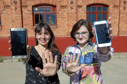 Susana Núñez e Iris Elena Muñoz muestran sus móviles en los alrededores de la Facultad de Comercio de Valladolid.-J. M. LOSTAU
