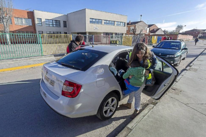 La cuidadora ayuda a bajar del taxi a uno de los dos niños que se desplazan de Aldeamayor de San Martín a La Pedraja de Portillo-Pablo Requejo