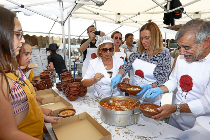 La delegada del Gobierno, Virginia Barcones, sirviendo unos platos de alubias junto a los organizadores, ayer en La Bañeza.-E. M.