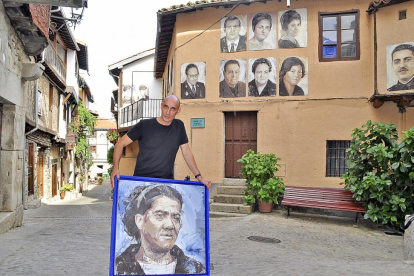 Florencio Maíllo, con uno de los cuadros de gran formato del proyecto artístico Retrata2-388, en una de las calles de Mogarraz donde, desde hace cinco años, cuelgan los retratos de sus antiguos vecinos.-ARGICOMUNICACIÓN