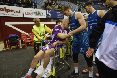 El lesionado Royo, en silla de ruedas, es saludado por dos jugadores del Gipuzkoa al abandonar el pabellón. / LOF