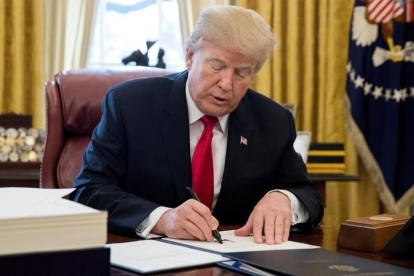 Trump firma la ley sobre la reforma fiscal, en el Despacho Oval de la Casa Blanca, en Washington, el 22 de diciembre.-/ EFE / MICHAEL REYNOLDS