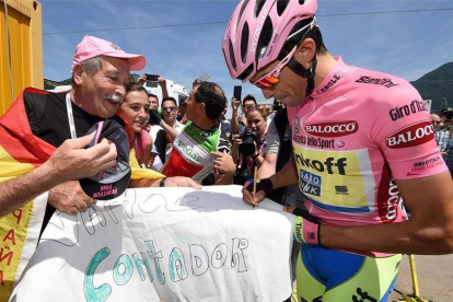 Contador firma autógrafos antes de comenzar la decimoctava etapa.-EFE