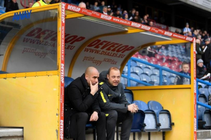 Guardiola charla con Rodolf Borrell, asistente suyo, en el banquillo del estadio del Huddersfield.-GETTY / LAURENCE GRIFFITHS