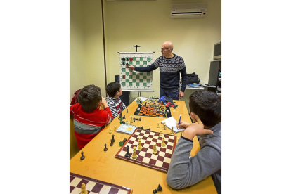 El profesor Fernando les enseña algunas jugadas para que den jaque mate en una partida, mientras algunos de los chavales apuntan las técnicas en un cuaderno.-MIGUEL ÁNGEL SANTOS