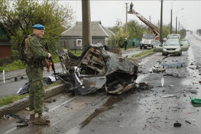 Un soldado permanece junto a un vehiculo calcinado en el lugar del ataque.-RPD / ALEXANDER ERMOCHENKO