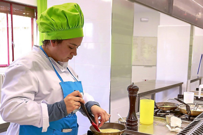 Una estudiante de cocina trabaja en la elaboración de un plato en los fogones de una escuela.-ICAL