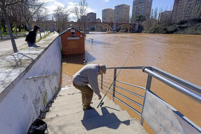 Un pescador en el Pisuerga, ayer, con la ribera baja inundada.-PABLO REQUEJO