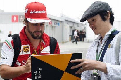 Fernando Alonso firma un autógrafo a un fan en el circuito de Suzuka.-Foto: AFP / TOSHIFUMI KITAMURA