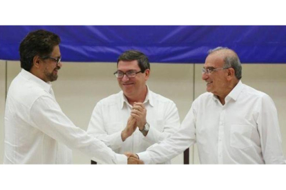 A la izquierda, el líder del equipo negociador de las FARC, Iván Márquez, se da la mano en La Habana con el representante gubernamental, Humberto de la Calle.-ALEXANDRE MENEGHINI / REUTERS