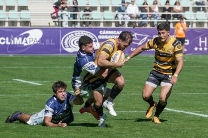 Dos jugadotres del VRAC intentan frenar el avance del Recoletas en La Nueva Balastera de Palencia.