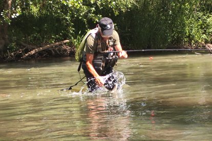 Un aficionado con una trucha en un cauce, antes de ser liberad.