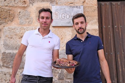 Carlos del Amo y Borja Martín a la puerta del restaurante con un plato de carne roja