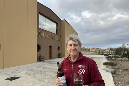 Javier Rupérez dando la espalda a las instalaciones de la moderna bodega de Rudeles con su pueblo Peñalba de San Esteban al fondo.