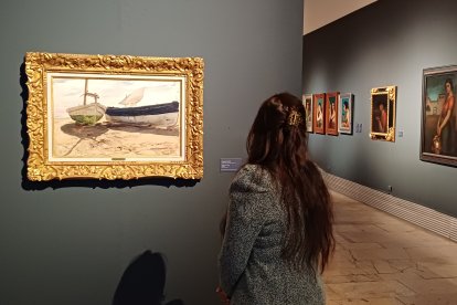 Una mujer contempla el óleo de 1900 ‘Barcas en la playa’, de Joaquín Sorolla.
