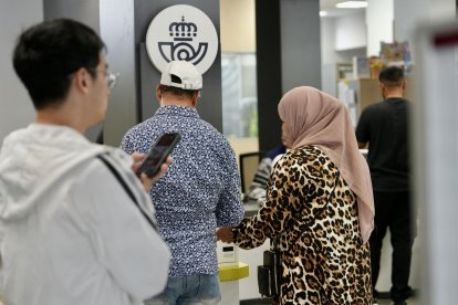 Dos personas tramitan su número para acceder al servicio de Correos.