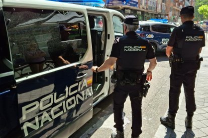 Dos agentes de la Policía Nacional delante de un furgón