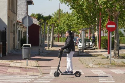 Un hombre cruza la calle Cañada Real con patinete por el paso de cebra