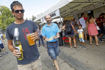 Dos asistentes a la feria con su bebida y comida.