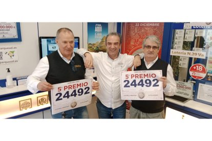 Los dos agraciados con el 5 Premio del Sorteo de Navidad y el lotero de Parquesol en Valladolid. E. M.