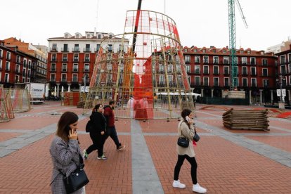 Transeúntes circulan cerca de la instalación de la base del árbol de Navidad en la Plaza Mayor. -J.M. LOSTAU
