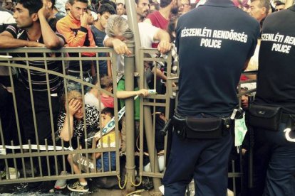 AP / PABLO GORONDI 

Los inmigrantes esperan detrás de una valla vigilada por la policía húngara delante de la estación de trenes más importante de Budapest, este martes.