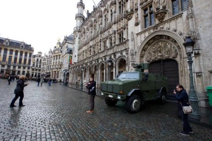 Dos personas se fotografían delante de un vehículo militar en la Gran Plaza que permanece solitaria. AFP / NICOLAS MAETERLINCK