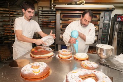 Rafael Mesonero y un empelado decoran y rellenan roscones en la Confitería Vitín