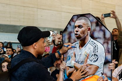 Mbappe firma un poster suyo de un joven aficionado a su llegada al aeropuerto de Villanubla.