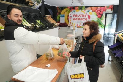 Calle Joaquín María Jalón. Ricardo Escudero, empleado en la frutería Rebeca, en el número 14, atiende a una clienta.
