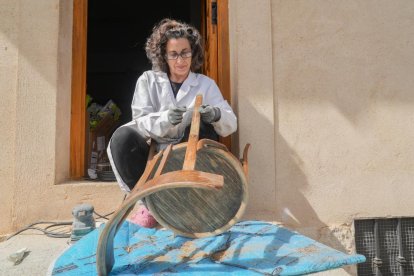 Elena Cadenas restaura una silla en la puerta de su casa. 
