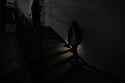 Una mujer sube a oscuras las escaleras de una vivienda.