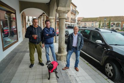 Felipe García, Ángel Fernández y Fernando Fernández se refugian de la lluvia en los soportales de la plaza Mayor
