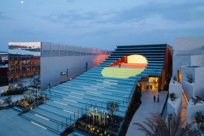 Una vista general del pabellón, con una escalinata y el interior iluminado
