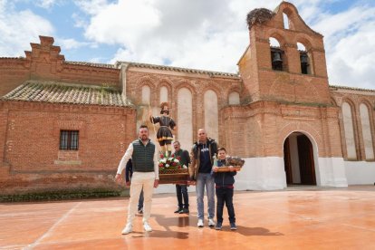 Varios jóvenes con la imagen de San Isidro delante de la iglesia de San Juan Bautista