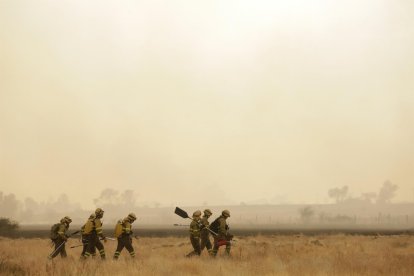 Varios bomberos tratan de extinguir un fuego en Miñambres de la Valduerna, León.