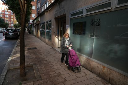 Una mujer con su carro de la compra pasa por delante de la academia Plaza Mayor en la calle de Las Mercedes.