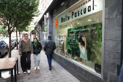 Varias personas pasan por delante de la peluquería Maite Pascual.