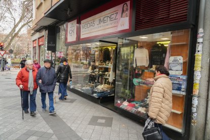 Varias personas pasan por delante de la tienda Modas Jiménez en la calle Tudela.