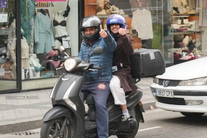 Dos personas saludan desde una moto en la calle Tudela.