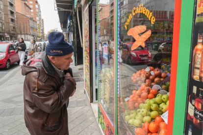 Un hombre mira el escaparate de una de las tiendas de comestibles de la calle Tudela.