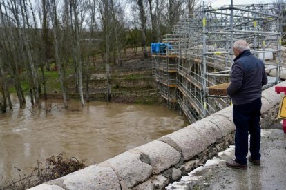 Un hombre observa el Cega a su paso por Megeces en Valladolid.