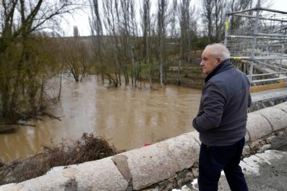 Un hombre observa el Cega a su paso por Megeces en Valladolid.