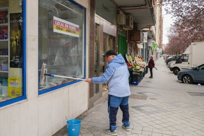 Un trabajador limpia el escaparate de la librería de Los Arcos en Valladolid.