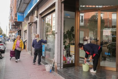 Dos operarios limpian la fachada de Kaferma en el Paseo de San Vicente.