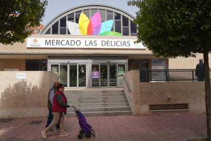 Dos personas pasan por delante del Mercado de Las Delicias.
