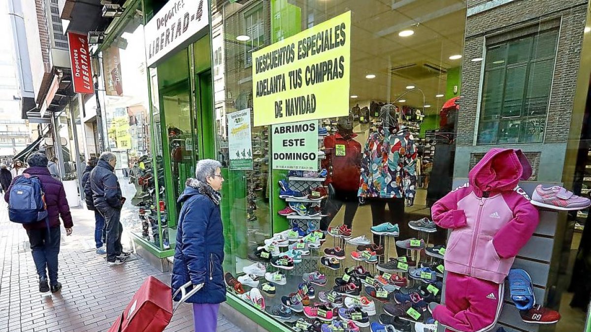 Una mujer con un carrito de compra observa las ofertas de un escaparate en la calle Teresa Gil.-J.M.LOSTAU