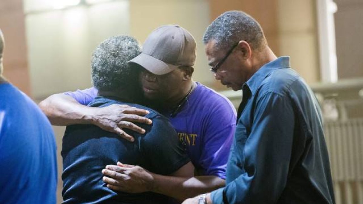 Varios feligreses se consuelan tars el tiroteo en la iglesia metodista de Charleston, esta madrugada.-Foto: EFE / RICHARD ELLIS