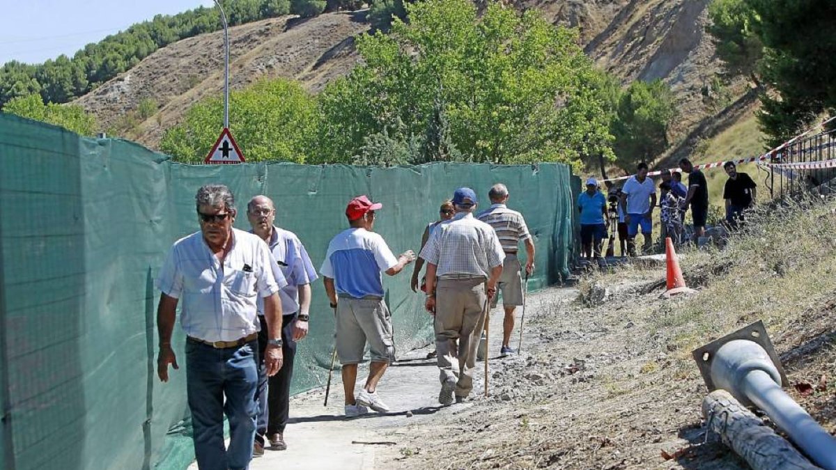 Los primeros vecinos cruzan por el paso habilitado para peatones junto a ñas obras del muro caído.-Juan Miguel Lostau